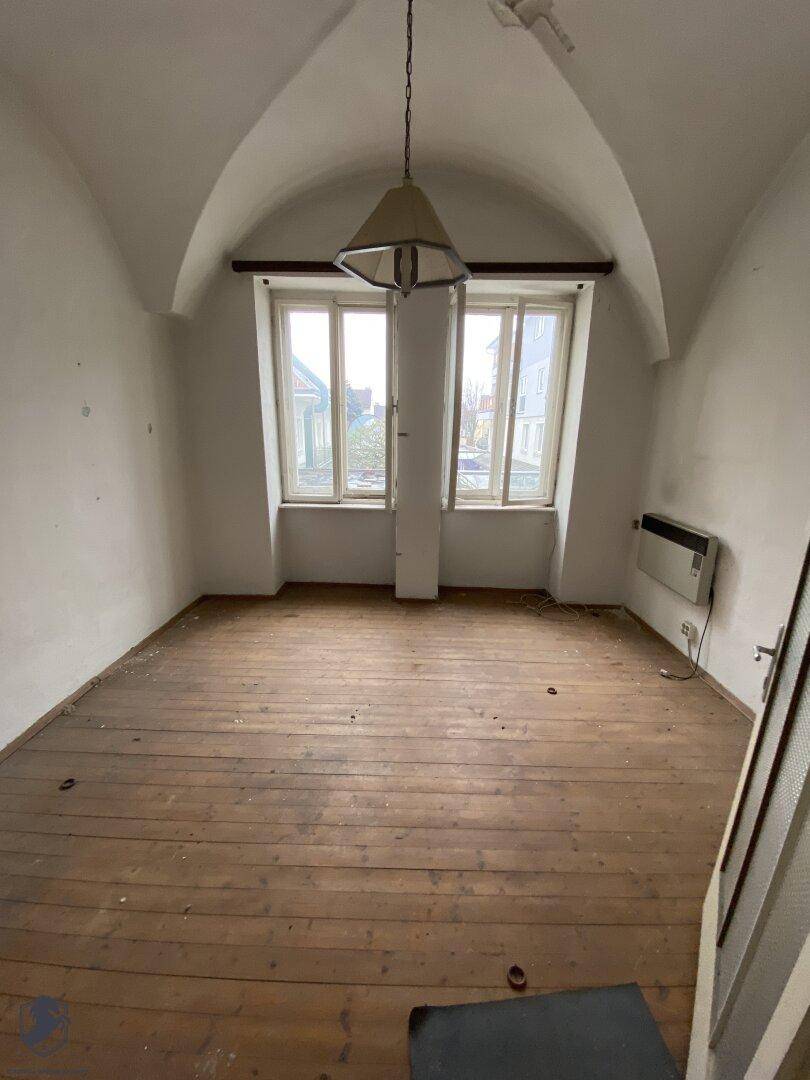 Heller Raum mit hoher Gewölbedecke und Holzdielenboden, der auf eine Renovierung wartet.