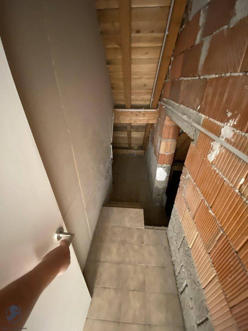 Unfertiger Kellerbereich mit sichtbaren Ziegelwänden und Holzdeckenbalken, bereit für Ausbau.