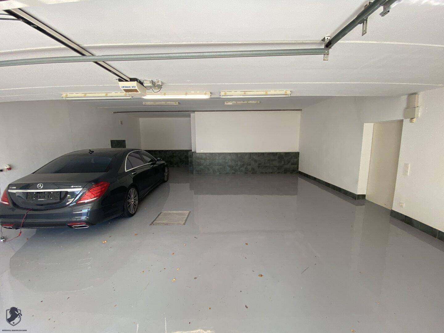 Geräumige Garage mit grauem Epoxidharzboden, weißen Wänden und Platz für mehrere Fahrzeuge.