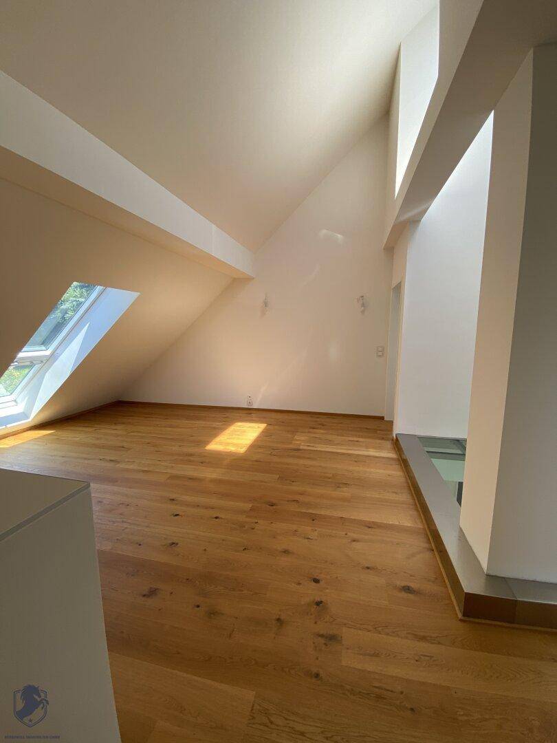 Geräumiges Zimmer im Dachgeschoss mit Holzboden, hohen Decken und Dachfenster.