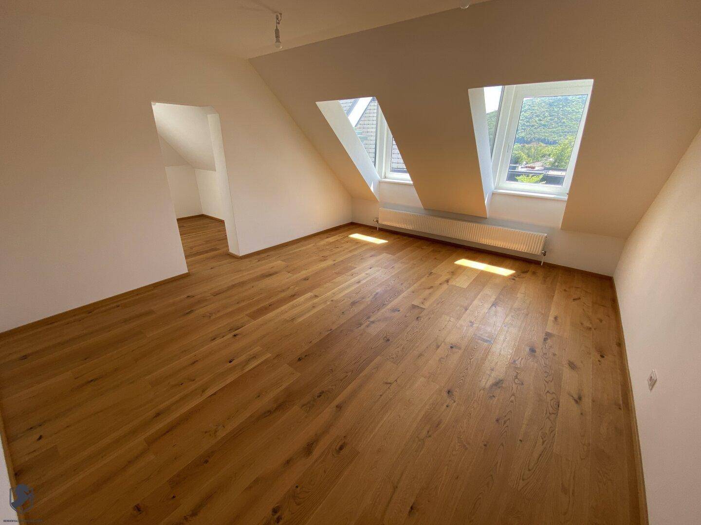 Helles Schlafzimmer im Dachgeschoss mit Holzboden, Dachfenstern und Bergblick.