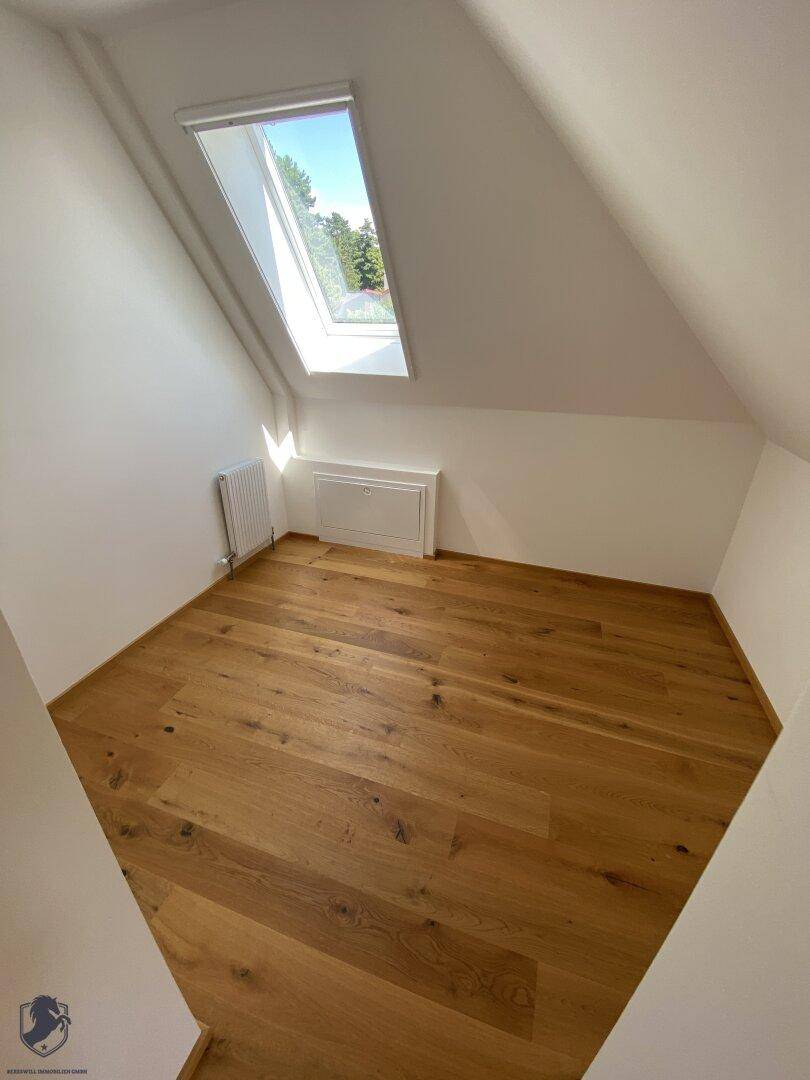 Kleines Zimmer im Dachgeschoss mit Holzboden, Heizung und einem Dachfenster.