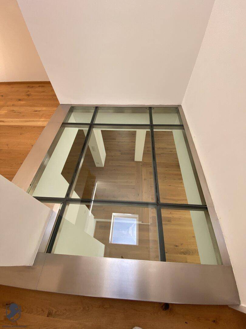 Moderner Flur mit Glasboden, der den Blick auf die darunterliegende Etage freigibt.