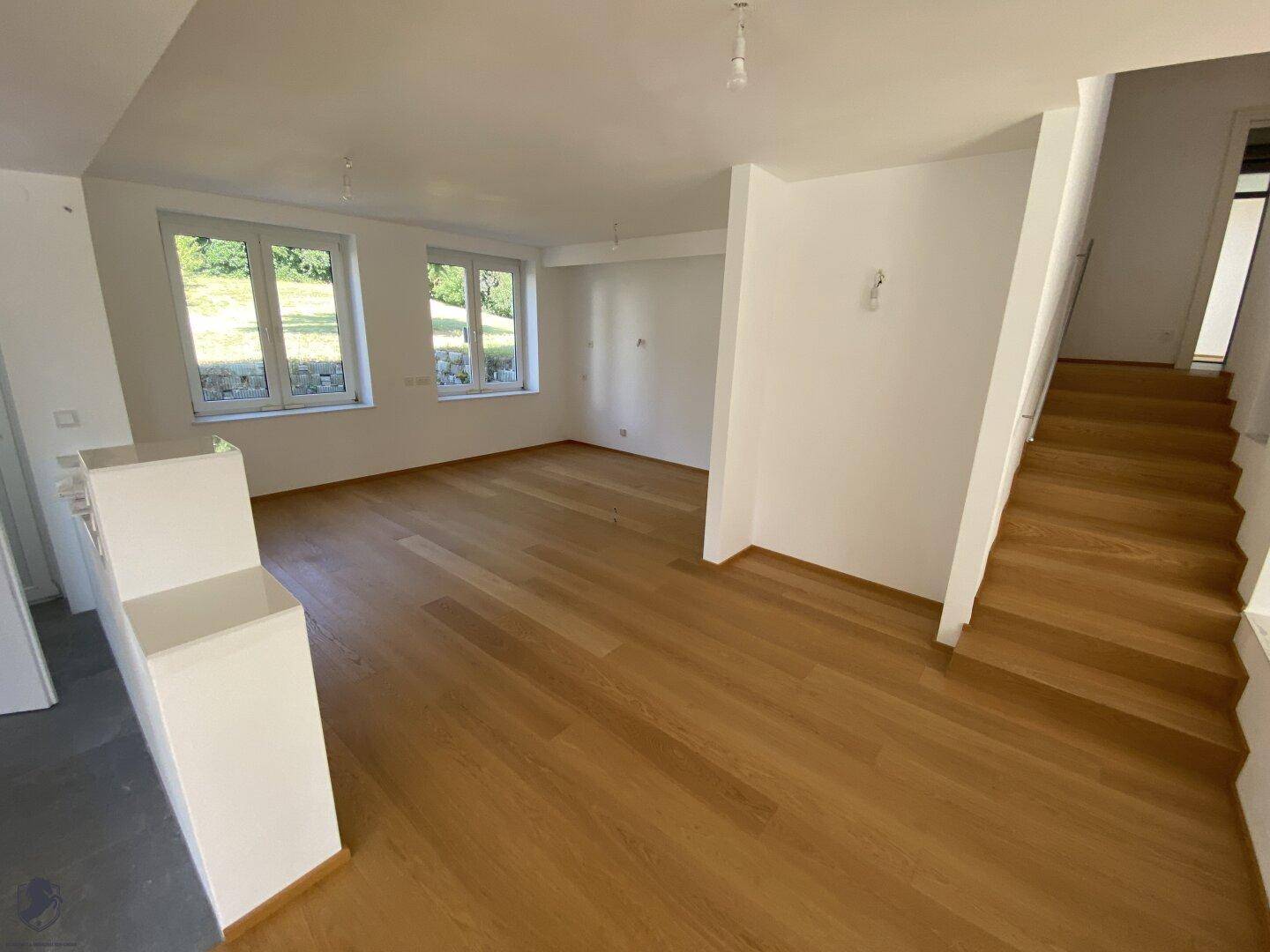 Heller Wohnbereich mit Holzboden und Treppe, die zu den oberen Etagen führt.