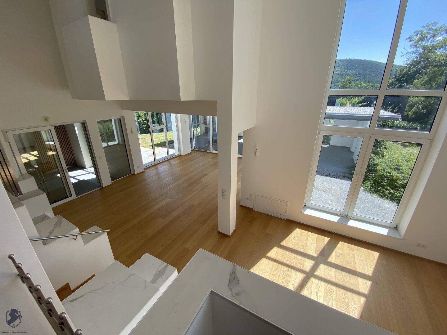 Großzügiger Wohnbereich mit hohen Decken, großen Fenstern und Bergblick.