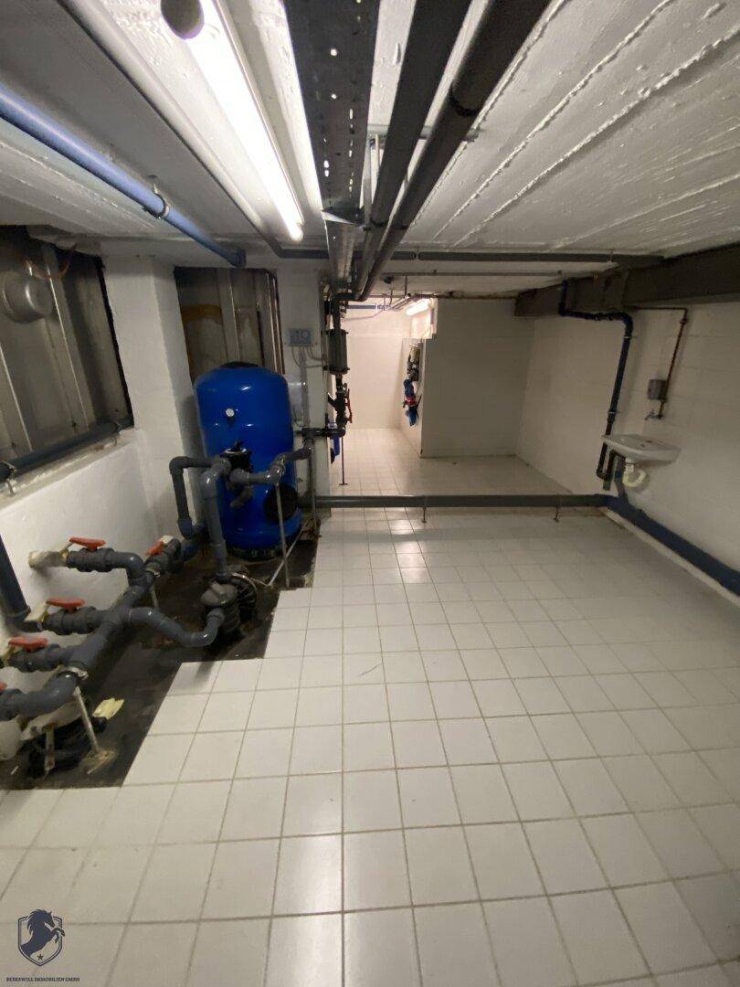 Technikraum mit Wasserpumpen, Rohren und gefliestem Boden.
