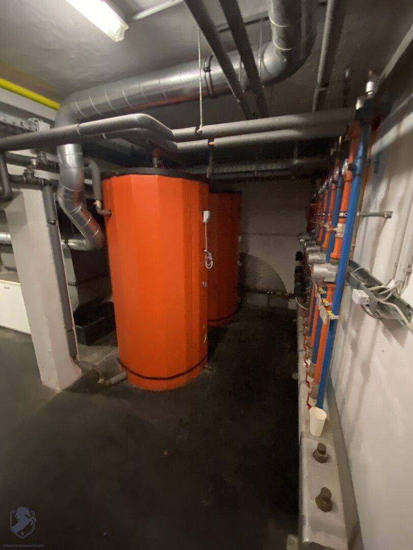 Heizungsraum mit großen Warmwasserspeichern und umfangreicher Rohrinstallation.