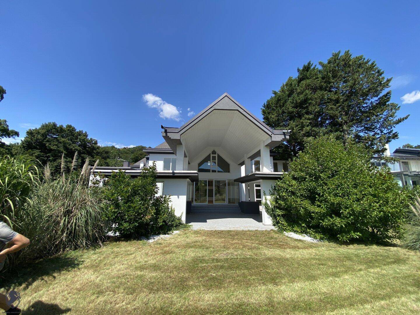 Moderne Villa mit markanter Architektur, großem Eingangsbereich und gepflegtem Vorgarten.