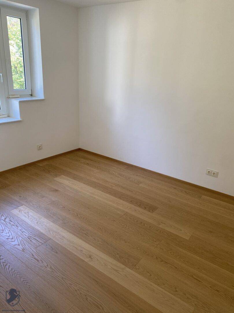 Helles, leeres Zimmer mit Eichenparkettboden und Fenster, bereit zur individuellen Gestaltung.
