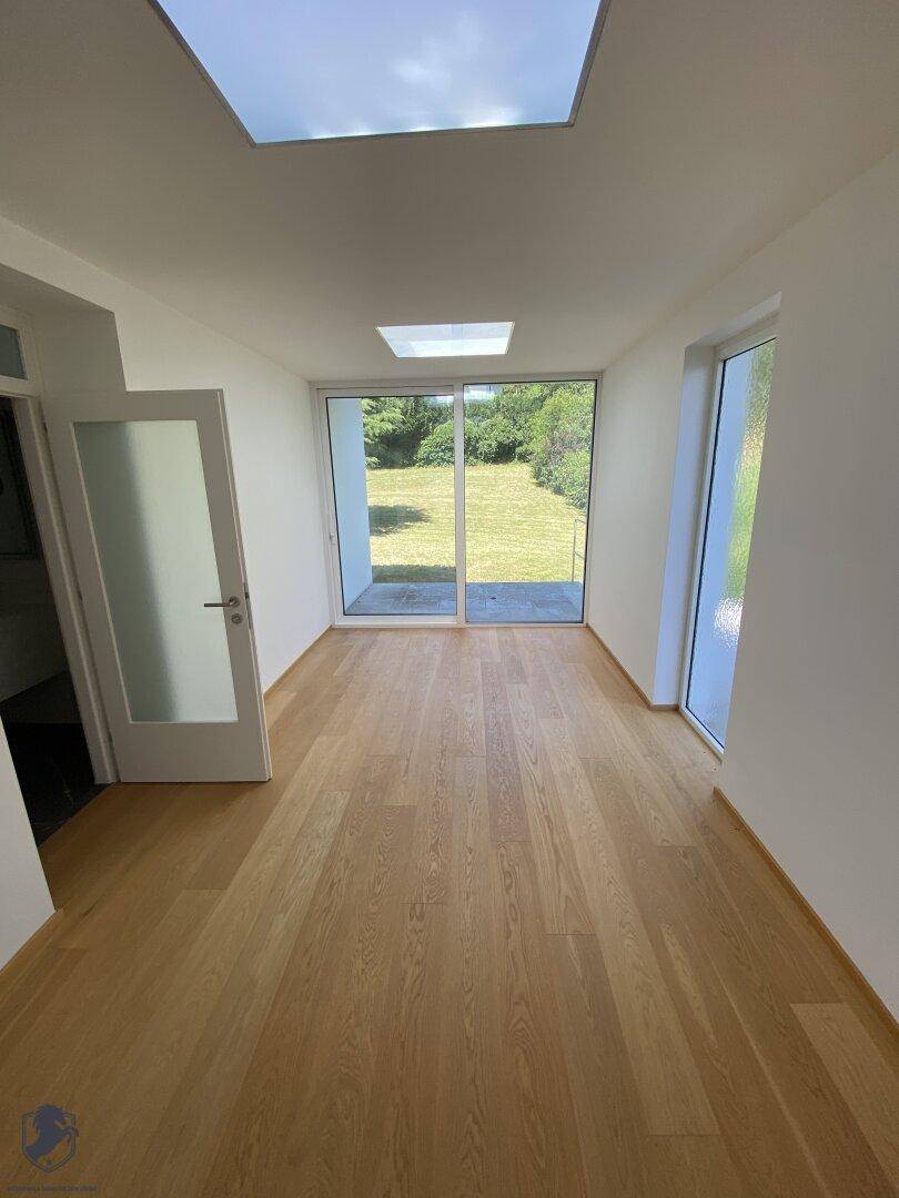 Heller Raum mit Holzboden, großen Fenstern zum Garten und zwei Dachfenstern für viel Tageslicht.