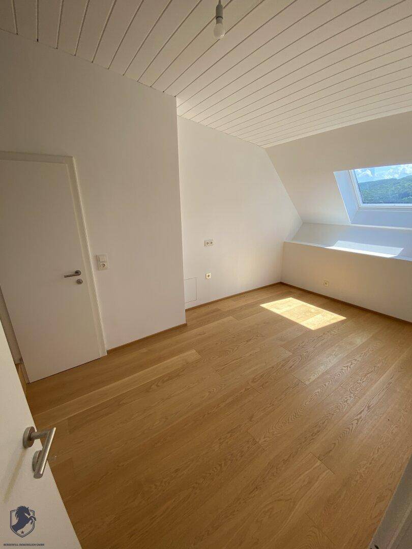 Gemütliches Zimmer im Dachgeschoss mit Holzboden und Dachfenster, das viel Licht spendet.