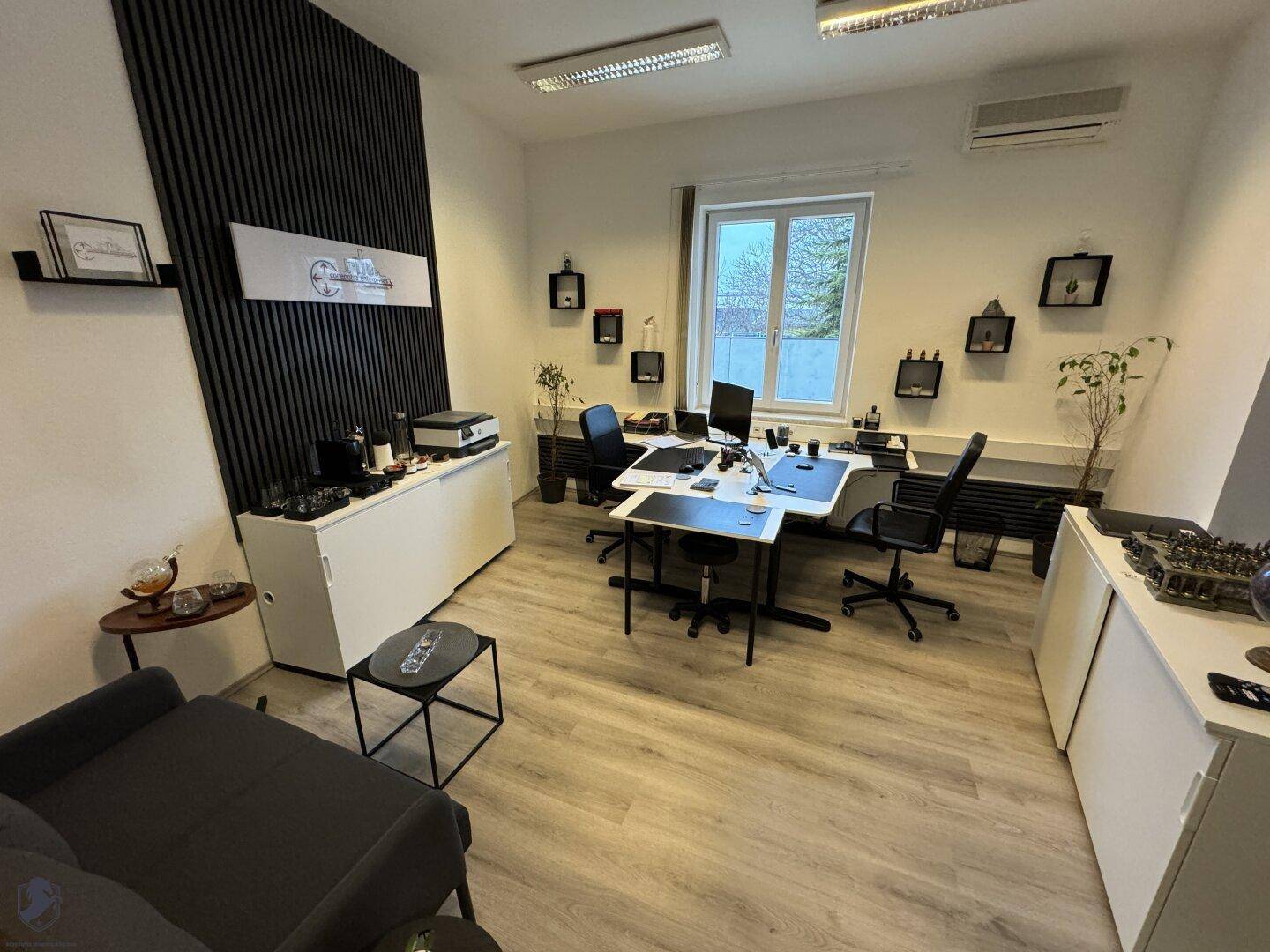 Modern eingerichtetes Büro mit Schreibtisch, Regalen und einem Fenster, das für natürliche Beleuchtung sorgt.