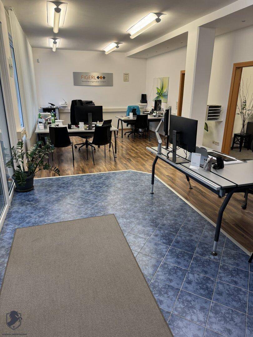 Großraumbüro mit unterschiedlichen Bodenbelägen, mehreren Arbeitsplätzen und moderner Einrichtung.