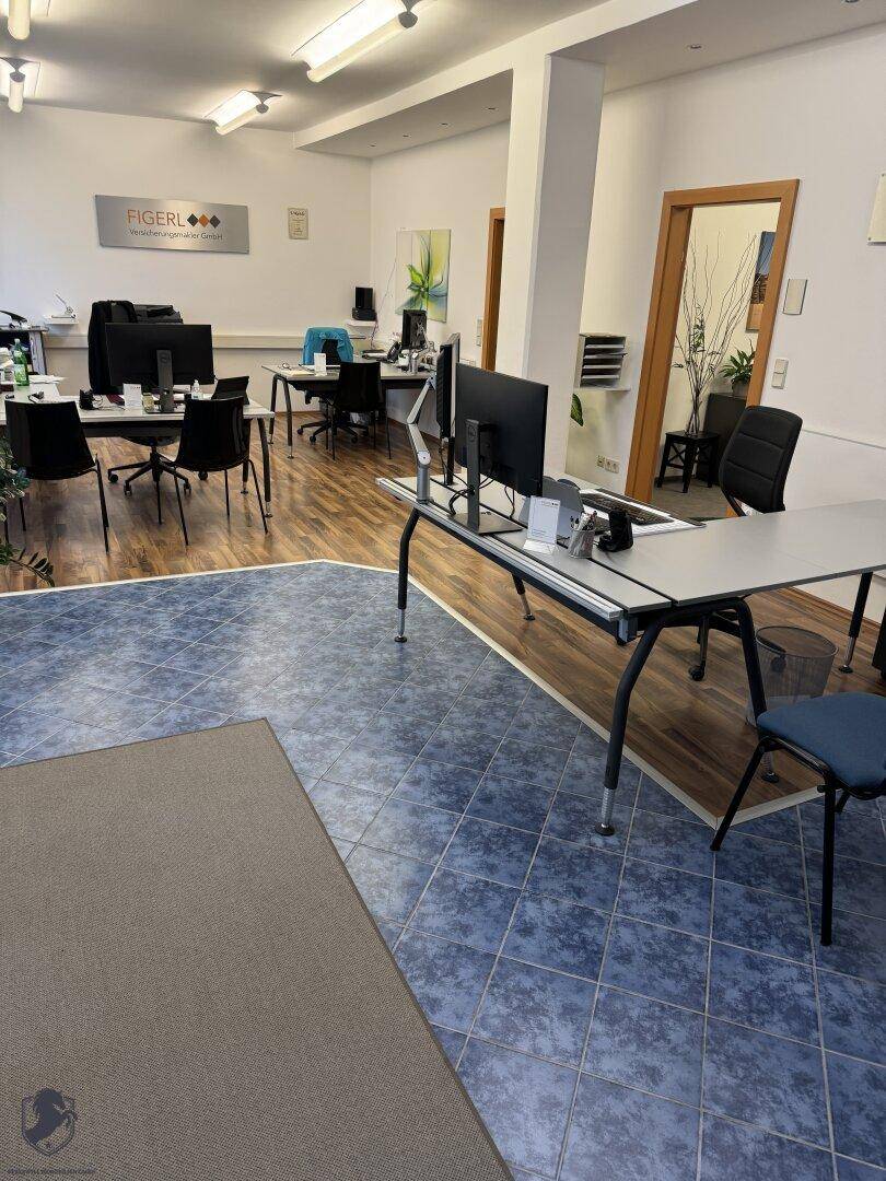 Großraumbüro mit unterschiedlichen Bodenbelägen, mehreren Arbeitsplätzen und moderner Einrichtung.