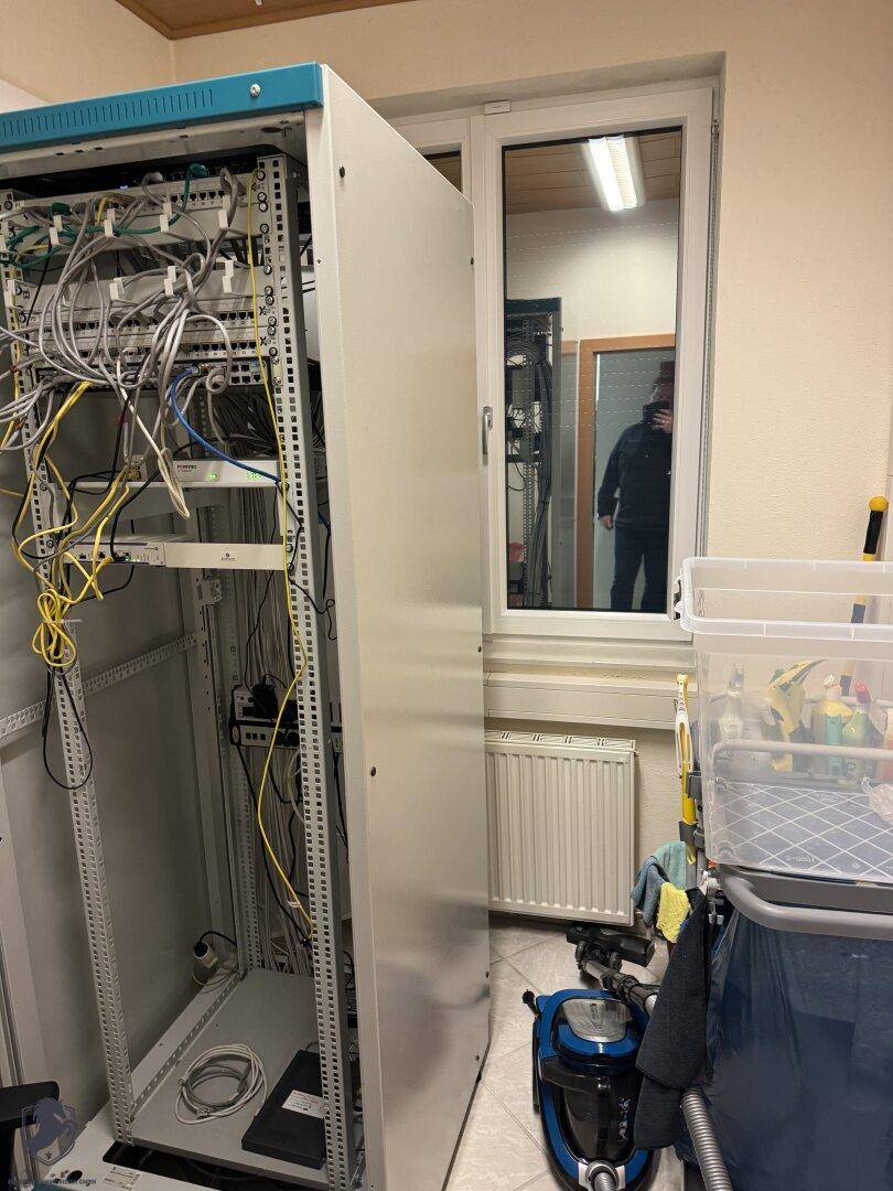 Serverraum mit Netzwerkschränken, Verkabelung und einem Fenster, das für Belüftung sorgt.