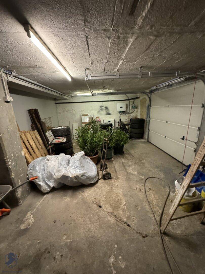 Geräumige Garage oder Lagerfläche mit Betonboden und einem großen Garagentor.