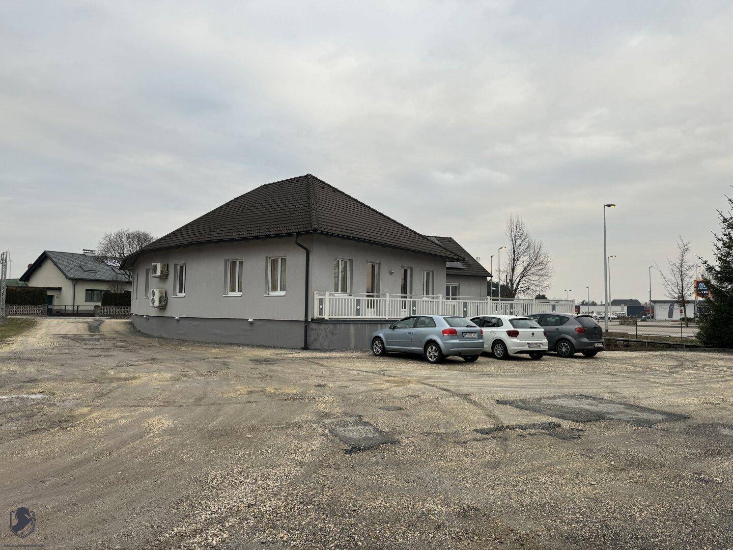 Seitenansicht des Bürogebäudes mit geschwungener Architektur und einem weitläufigen Parkplatzbereich.