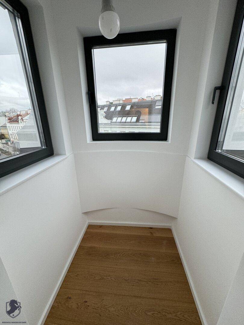 Kleiner, heller Bereich mit Holzboden und einem großen Fenster, das einen Blick nach draußen bietet.