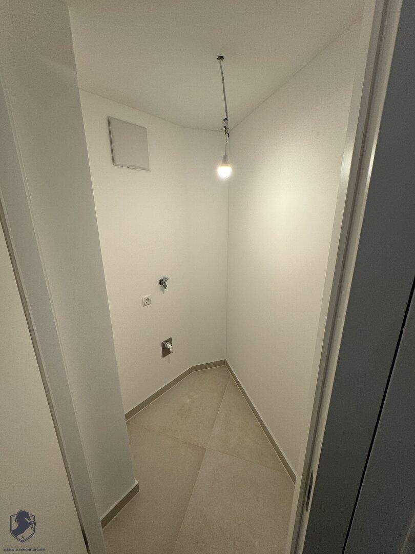 Kleiner Hauswirtschaftsraum mit Fliesenboden und Anschlüssen für Waschmaschine oder Trockner.