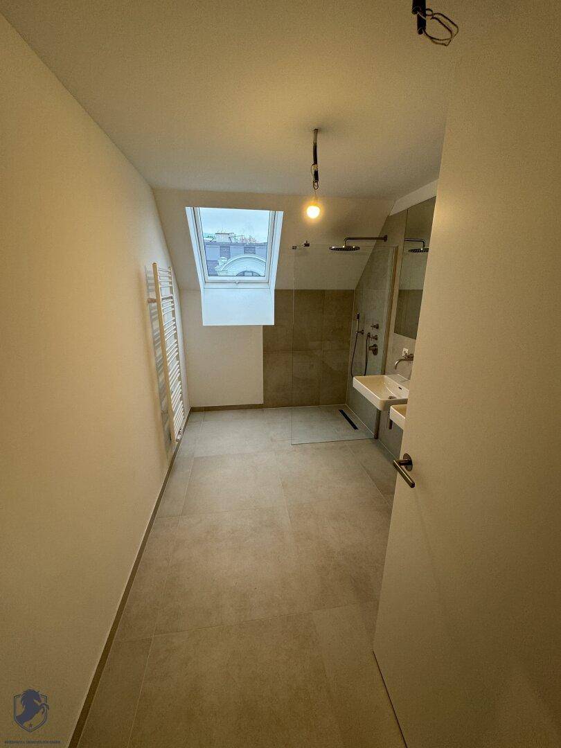 Modernes Badezimmer im Dachgeschoss mit begehbarer Dusche, Doppelwaschbecken und Dachfenster.