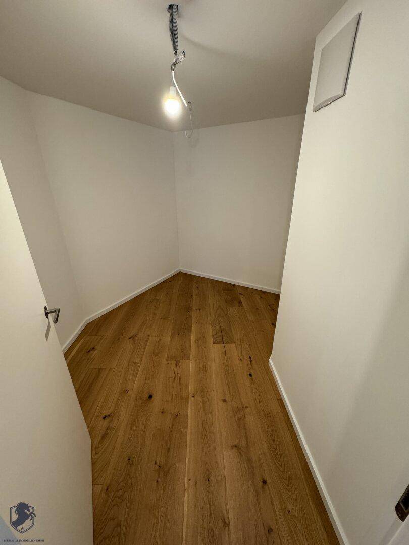 Kleiner Raum mit Holzboden und weißen Wänden, ideal als Abstellraum oder begehbarer Kleiderschrank.