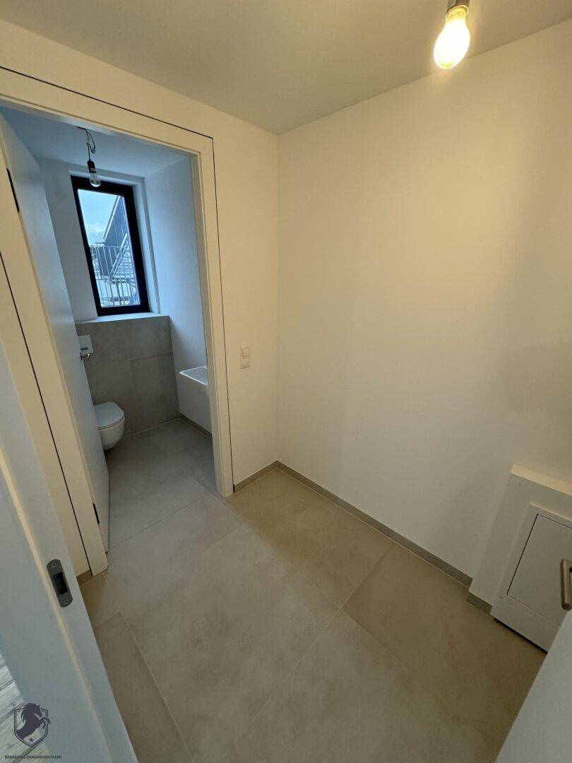 Heller Eingangsbereich mit Fliesenboden und Zugang zu einem Badezimmer oder Gäste-WC.