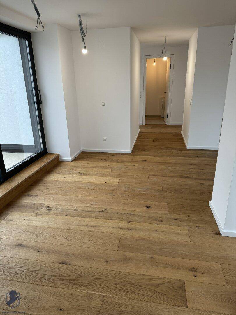 Heller Flur mit Holzboden und Blick in den offenen Wohnbereich mit Zugang zur Terrasse.