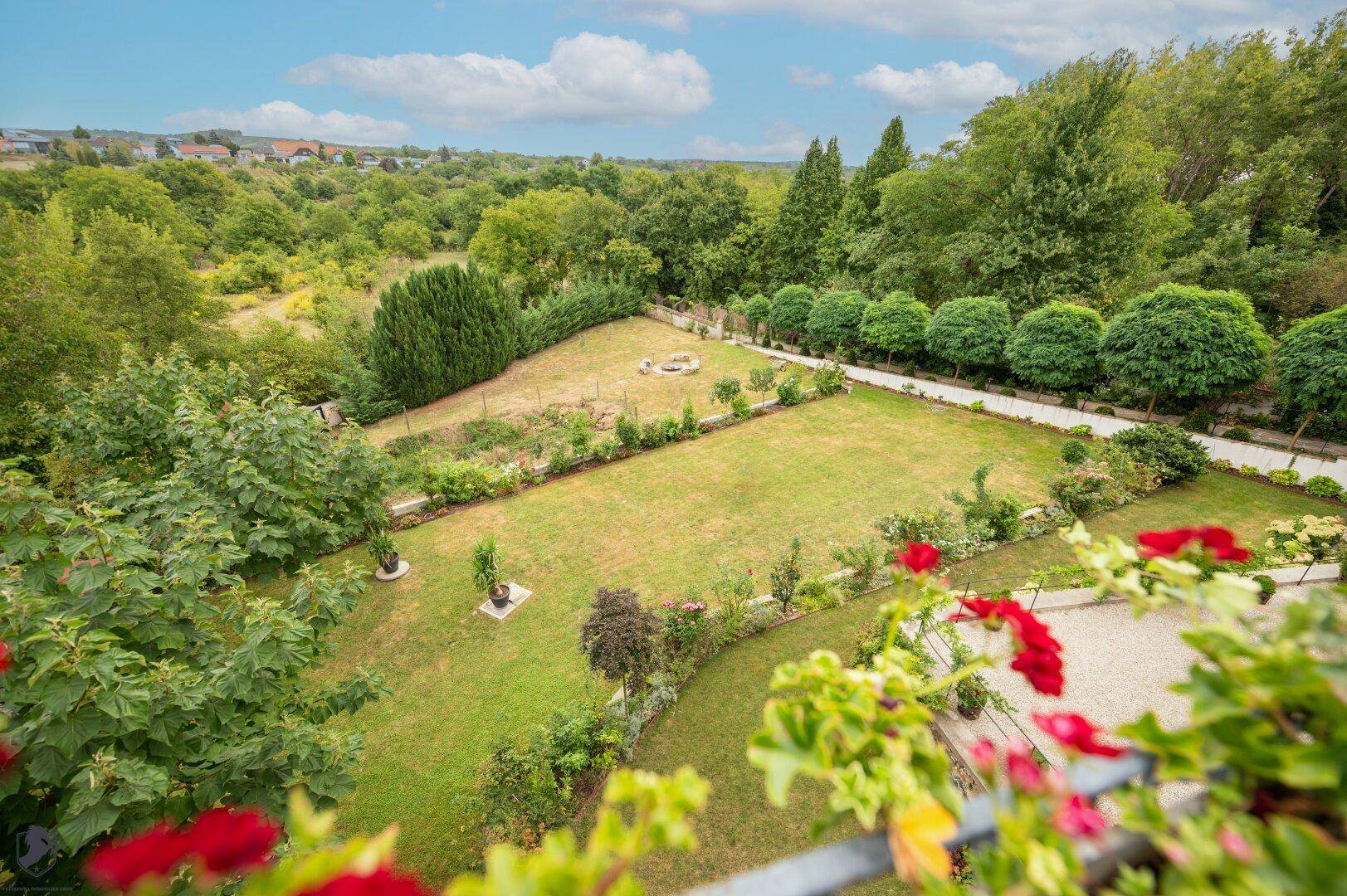 Panoramablick auf den weitläufigen Garten und die umliegende grüne Landschaft.