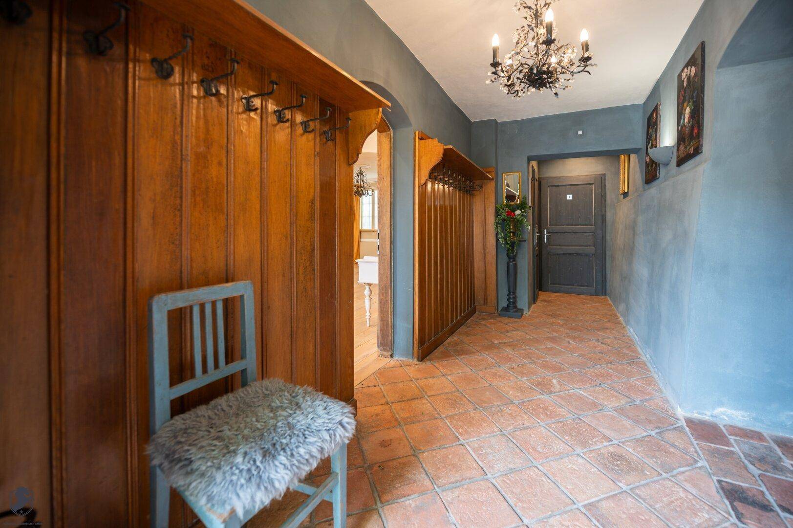 Rustikaler Eingangsbereich mit Holzvertäfelung, Terrakottaboden und Garderobe.