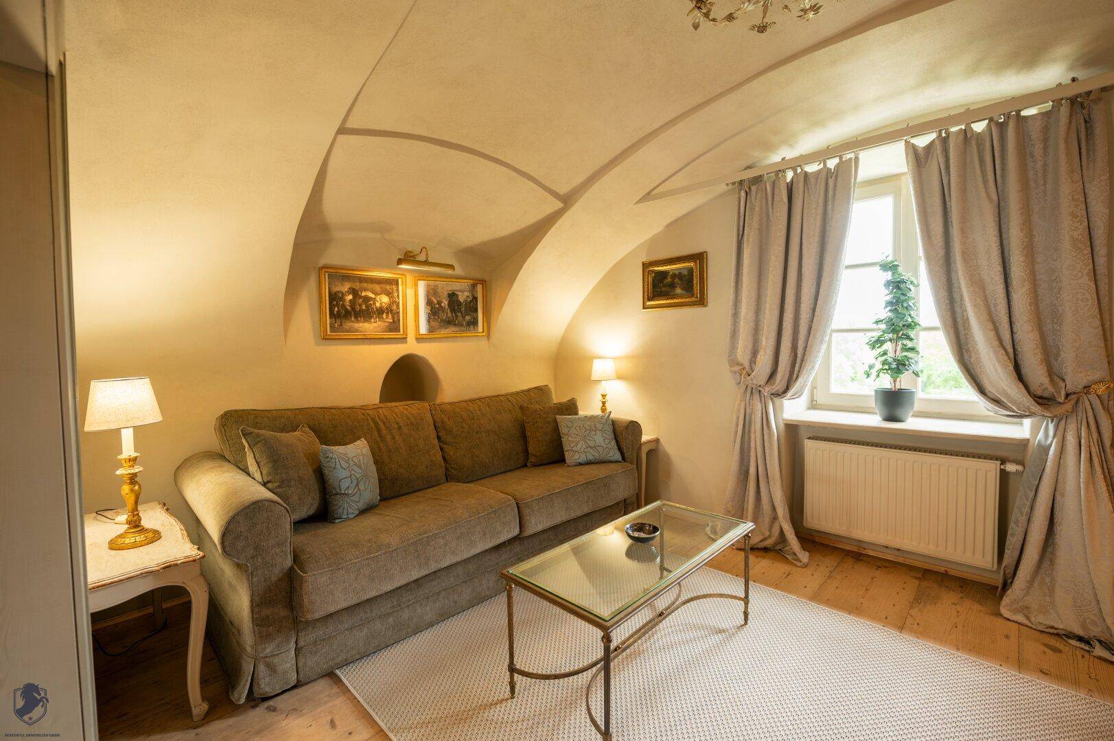 Gemütliches Wohnzimmer mit Sofa, Gewölbedecke und hellem Holzplankenboden.