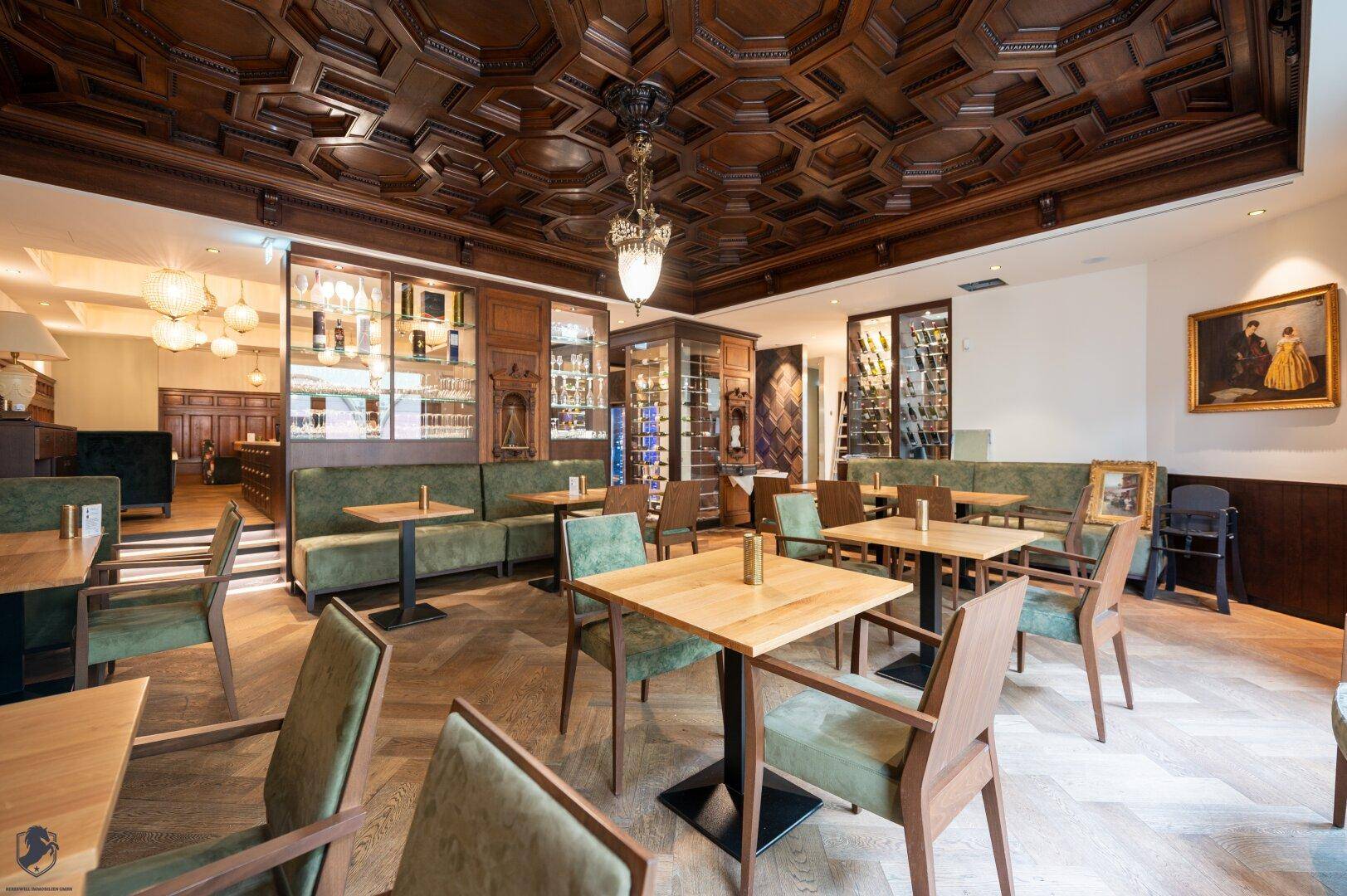 Stilvoller Restaurantbereich mit dunkler Holzdecke, Fischgrätparkett und integrierten Weinschränken.