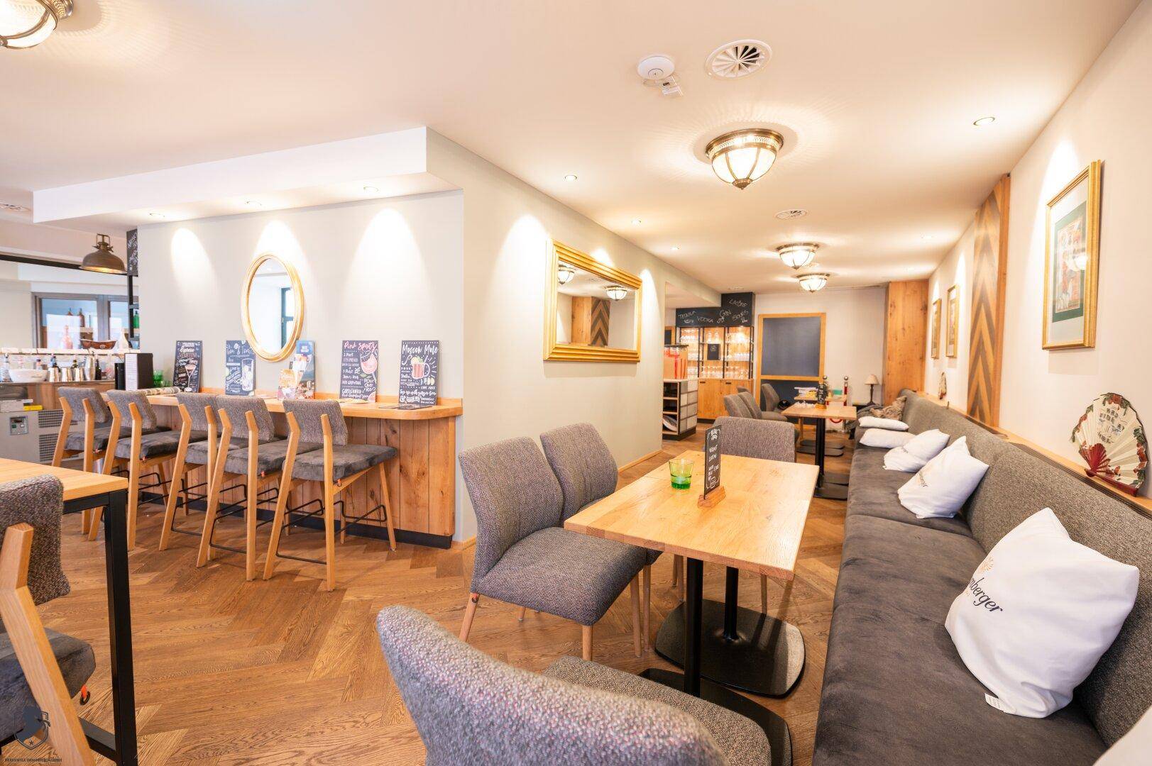 Heller Restaurantbereich mit Holzboden, bequemen Sitzbänken und Barhockern.