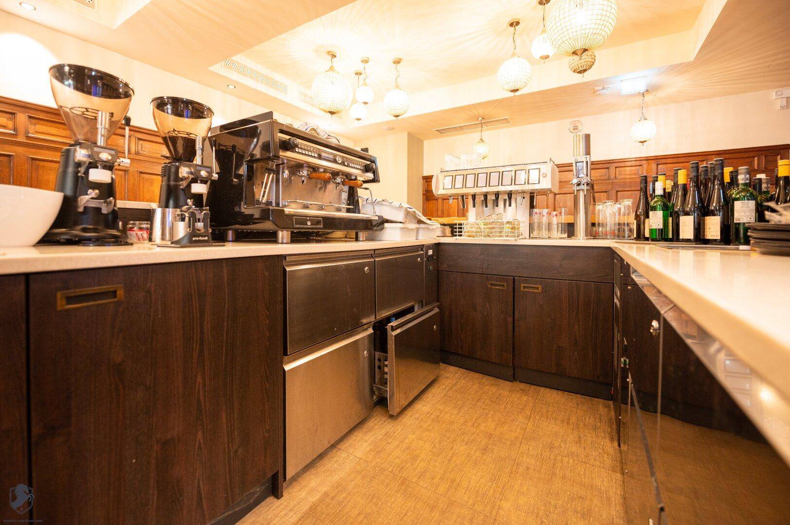 Moderne Barista-Station mit professionellen Kaffeemaschinen und dunklen Holzschränken.