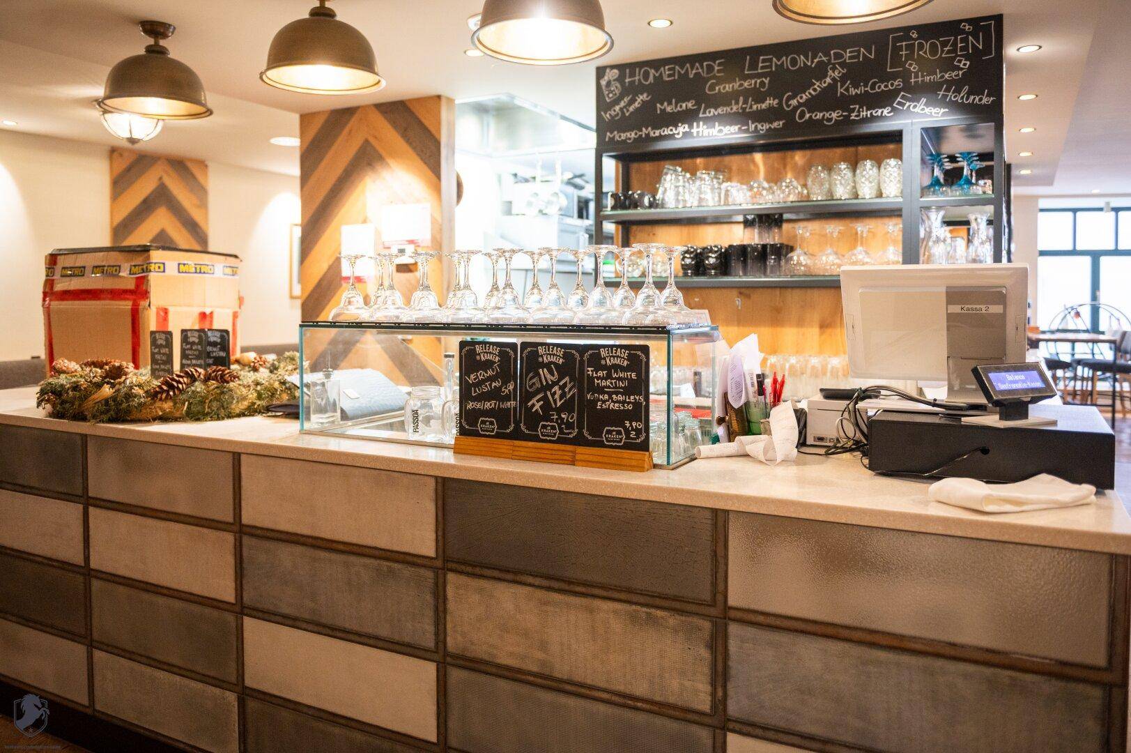Moderne Bar mit kreativer Wandgestaltung und einer Auswahl an Getränken und Gläsern.