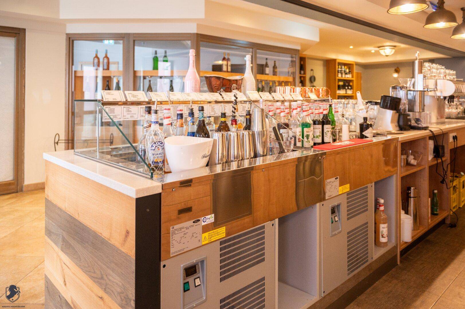 Helle Bar mit Holzverkleidung, professionellen Geräten und einer großen Getränkeauswahl.
