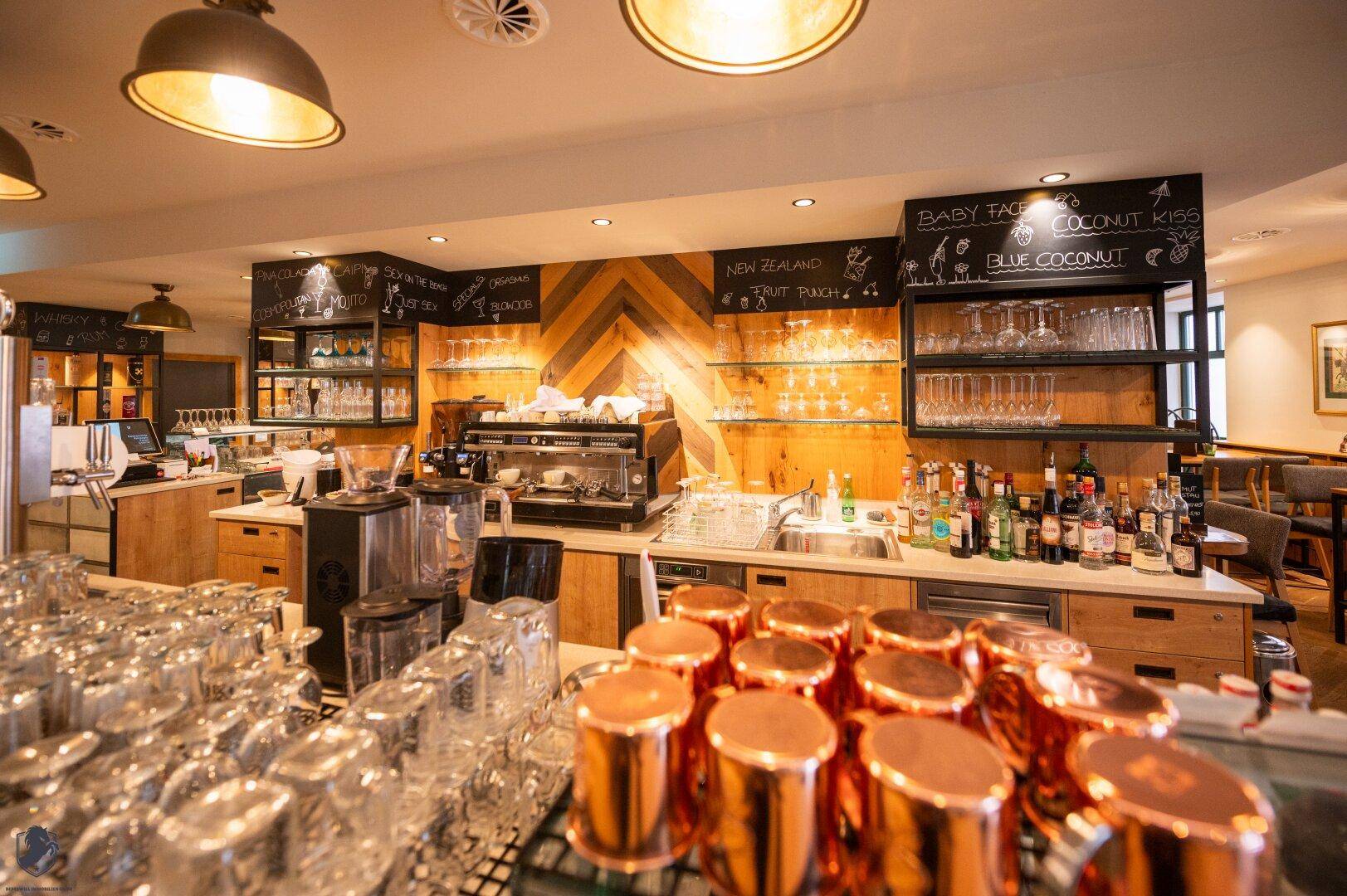 Geräumige Bar mit Holzdetails, vielen Gläsern und einer professionellen Kaffeemaschine.