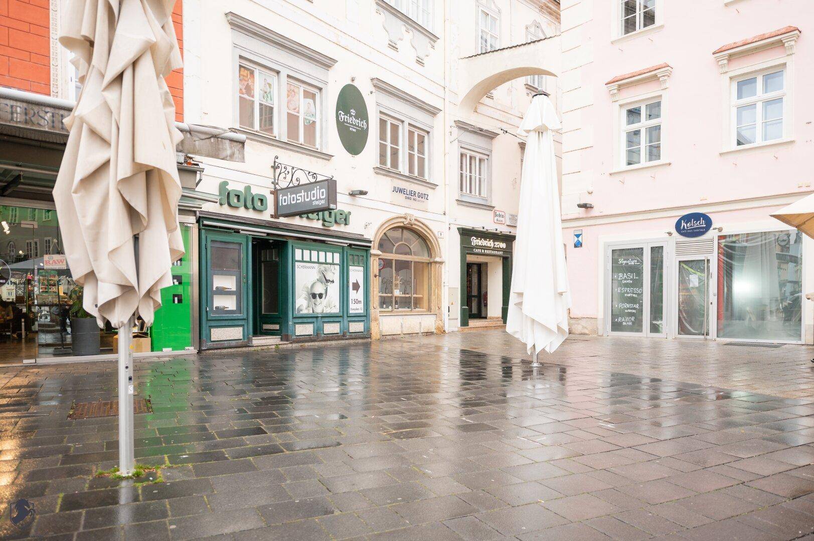Eine belebte Gasse mit verschiedenen Geschäften und Restaurants, darunter "Friedrich 2700".