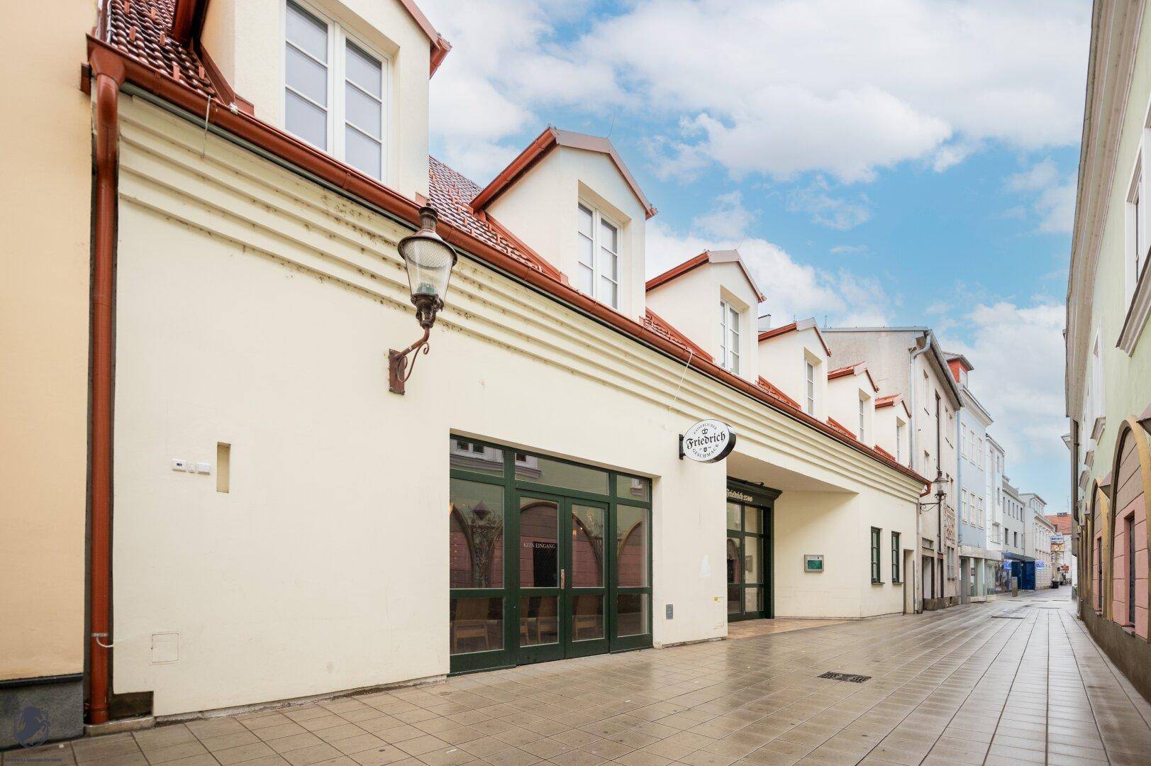 Historische Gebäudezeile mit traditionellen Dächern und einem Café-Eingang an der Straße.