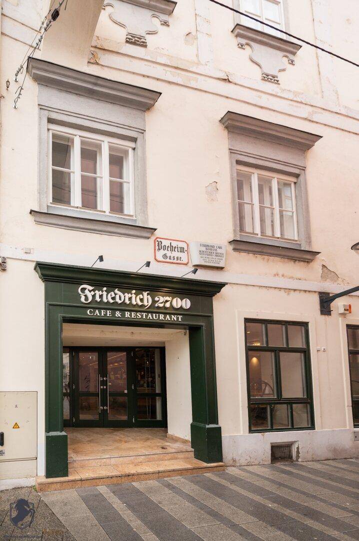 Fassade eines historischen Gebäudes mit Café-Eingang und großen Fenstern.