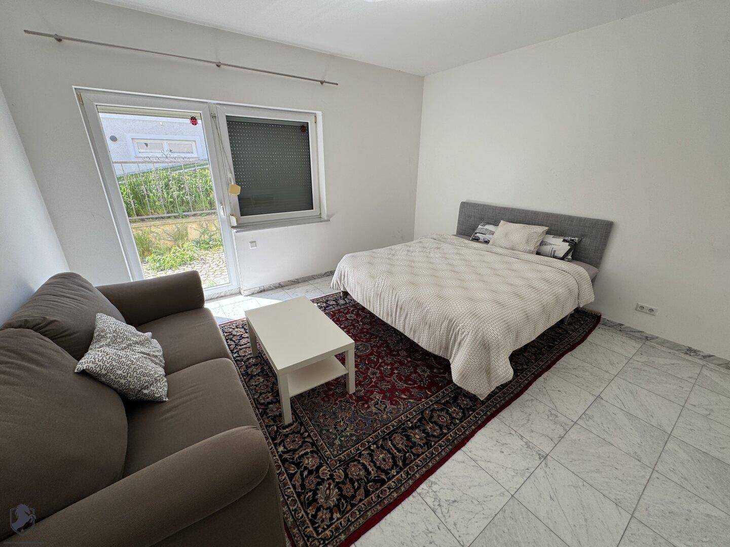 Gemütliches Schlafzimmer mit Bett, Sofa und direktem Zugang zu einem kleinen Außenbereich.