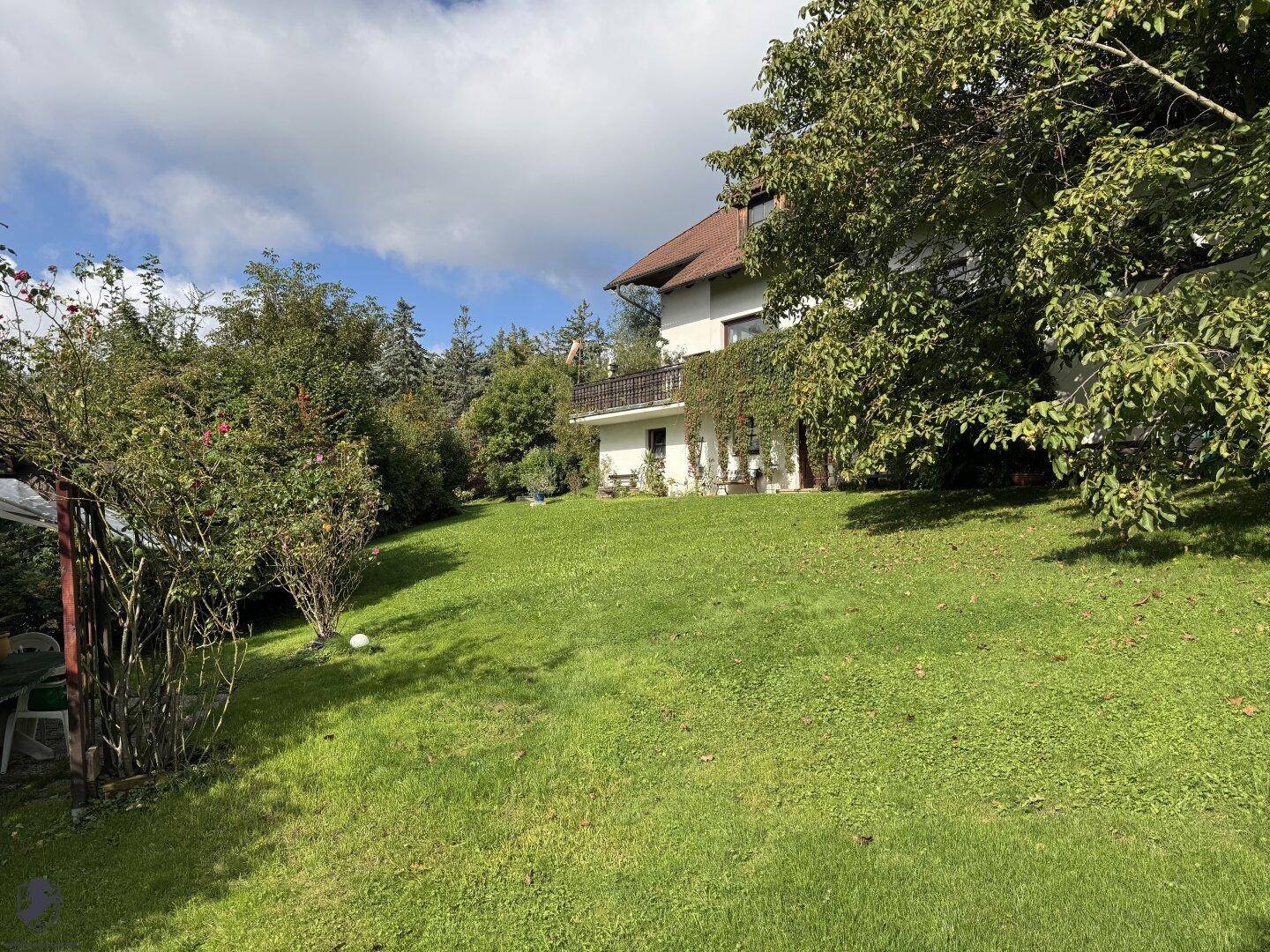 Weitläufiger Garten mit gepflegtem Rasen und Blick auf das Wohnhaus mit Balkon.