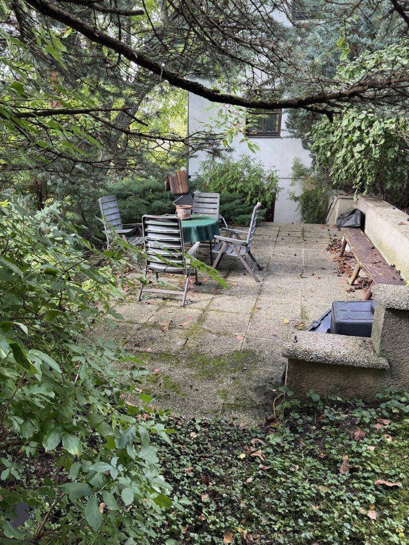 Rustikale Terrasse mit Gartenmöbeln und umgebender Vegetation, ideal für Entspannung.