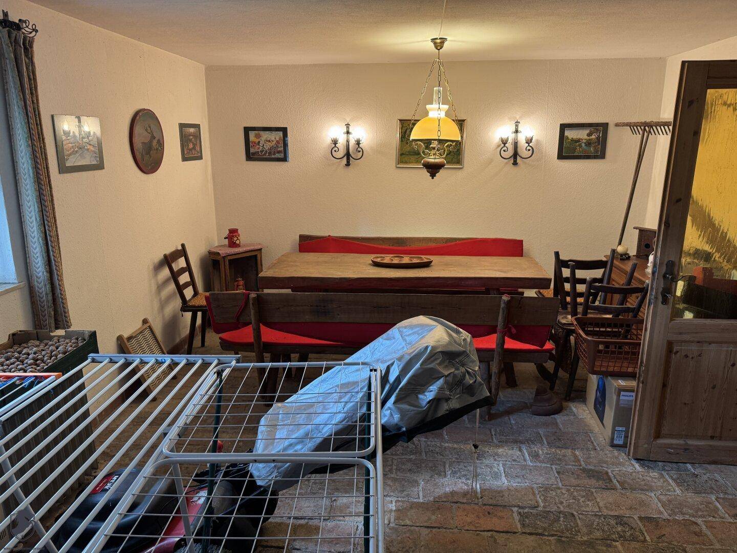 Traditioneller Essbereich mit großem Holztisch, Bänken und Fliesenboden.