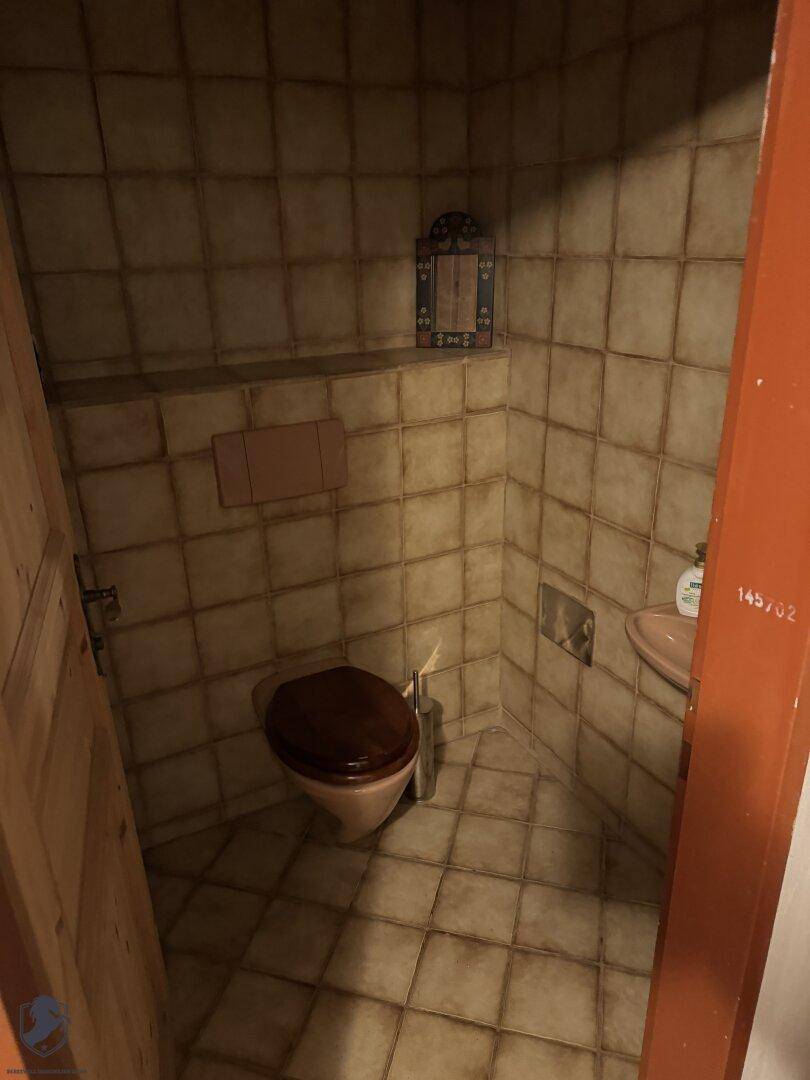 Kleines Gäste-WC mit Fliesen an Wänden und Boden sowie einem Waschbecken.