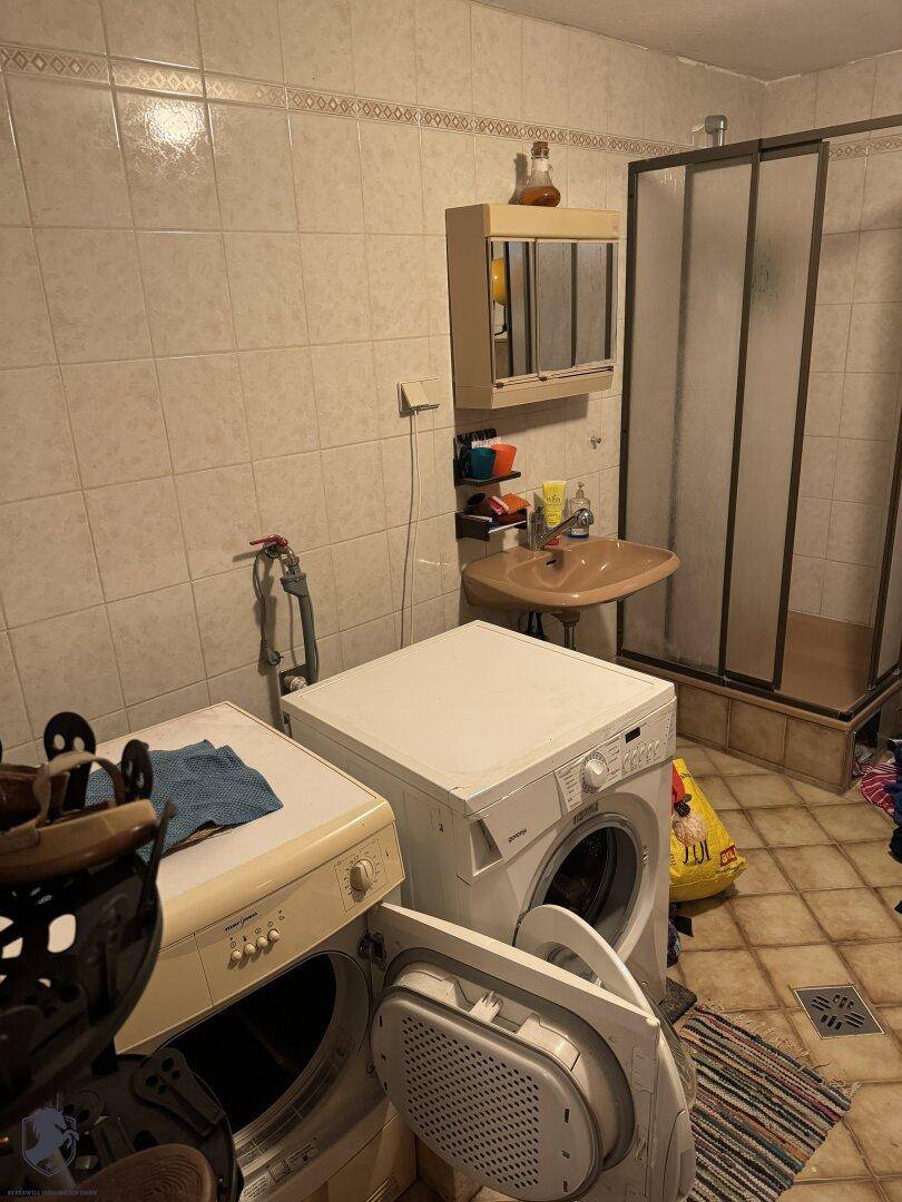 Badezimmer mit Duschkabine, Waschbecken, Waschmaschine und Trockner.