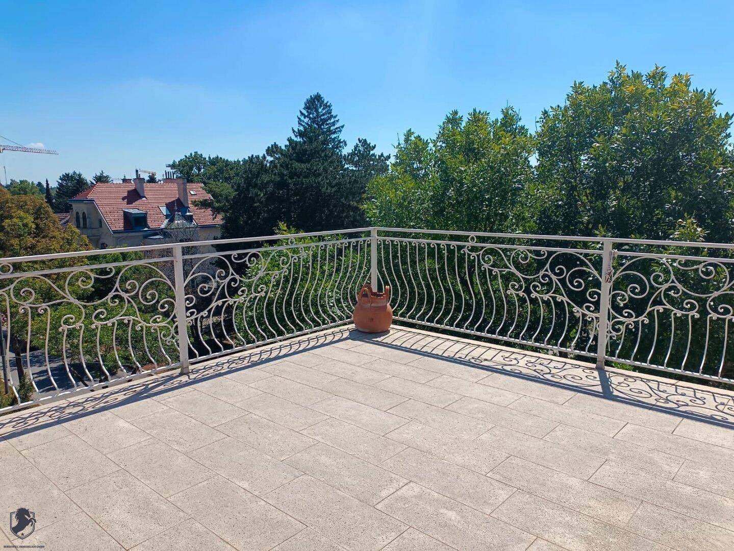 Geräumige Dachterrasse mit Fliesenboden und schmiedeeisernem Geländer, bietet weite Aussicht.