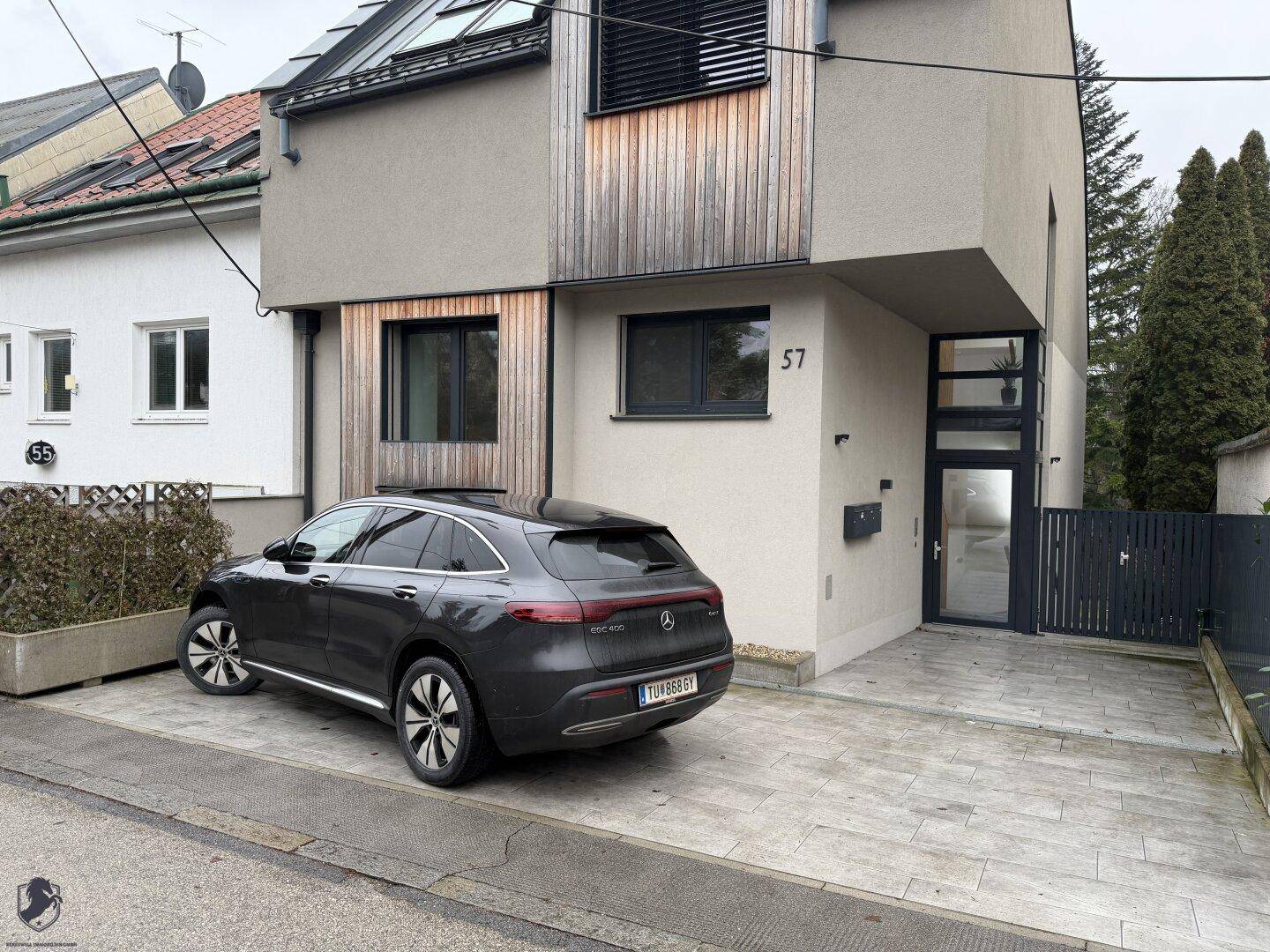 Nahaufnahme der modernen Hausfassade mit Holzelementen und der Einfahrt zum Gebäude.