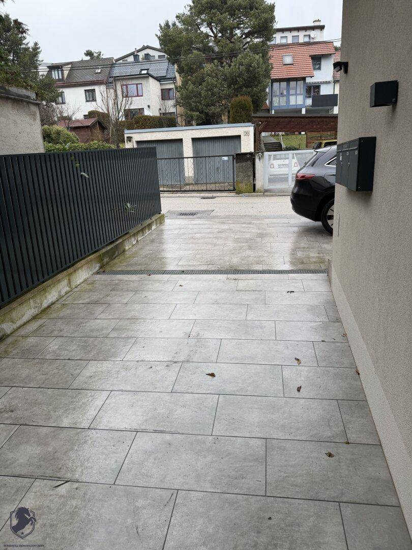 Gepflasterter Zugangsbereich zum Haus mit einer modernen Zaunanlage und Blick auf die Nachbarschaft.