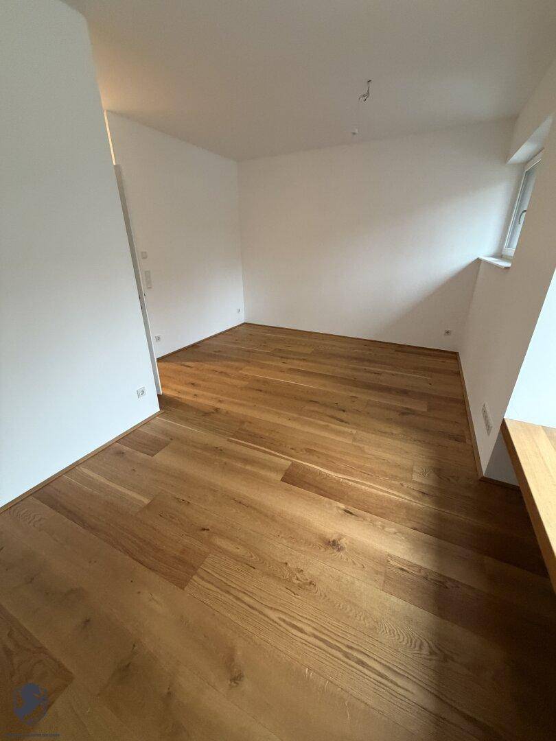 Helles Zimmer mit hochwertigem Holzboden und weißen Wänden, bereit zum Einrichten.