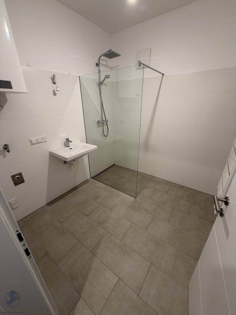 Modernes Badezimmer mit ebenerdiger Dusche, Wand-WC und beheiztem Handtuchhalter.